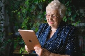 Elderly woman watching virtual memorial service on an ipad.